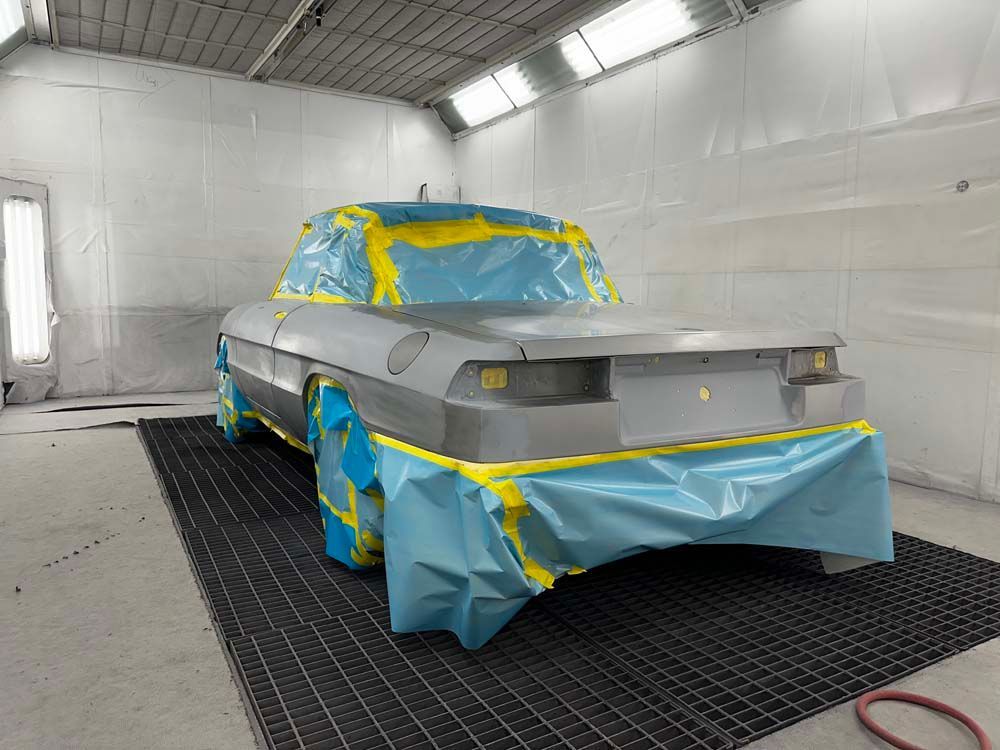 A car is being painted in a paint booth.