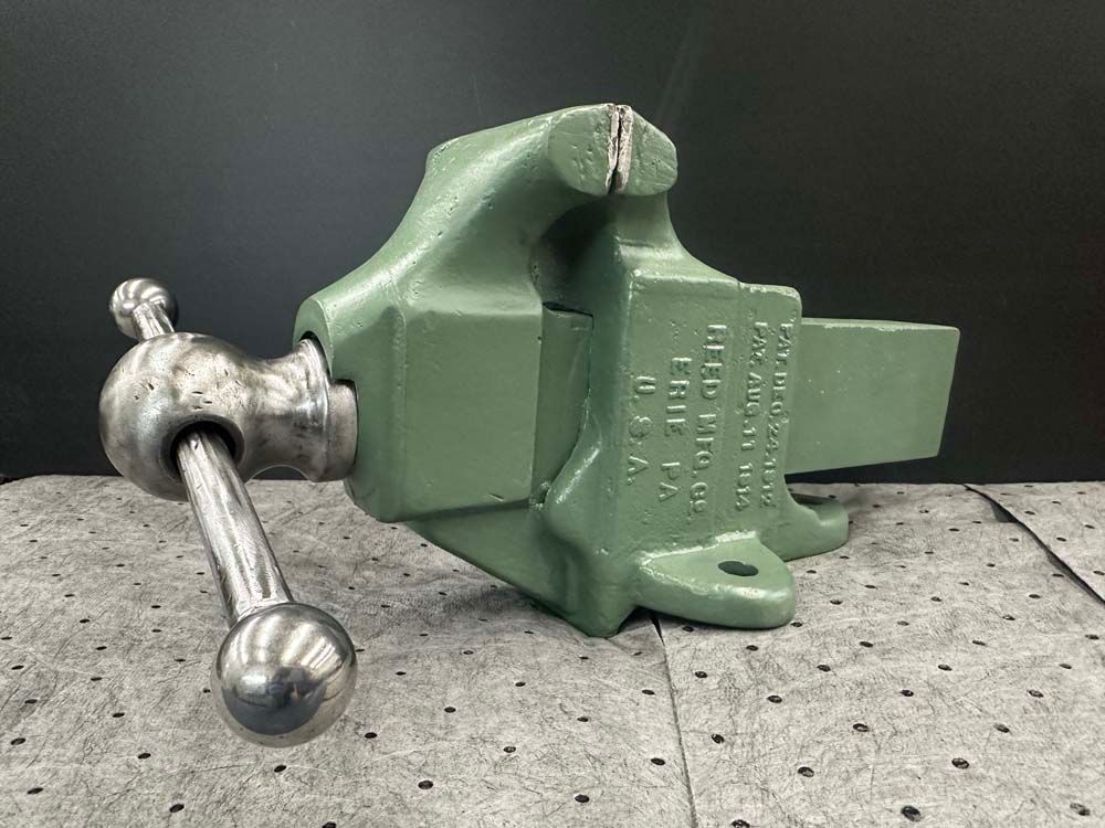 A green vise is sitting on top of a table.