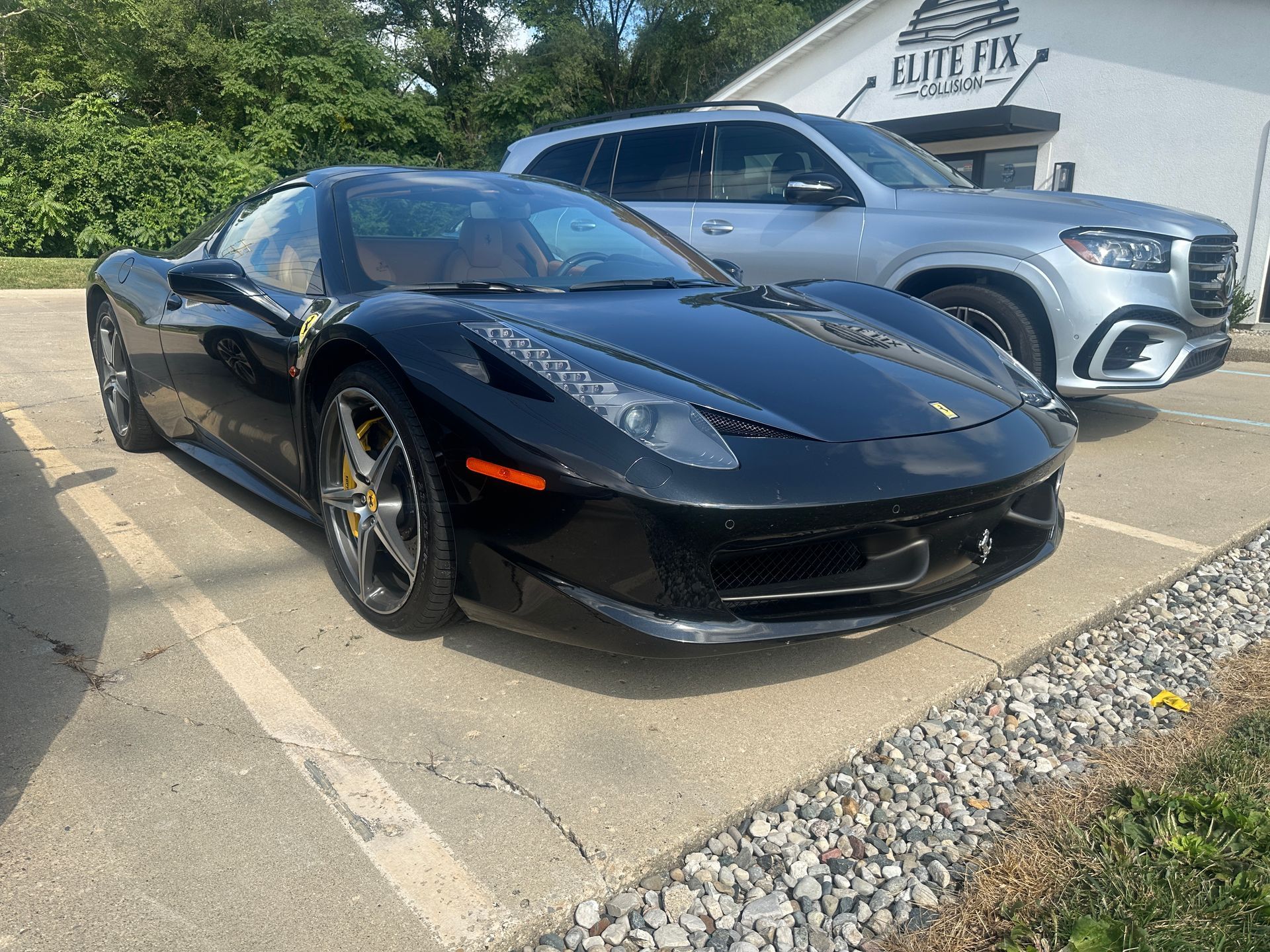 Black Ferrari parked next to a silver SUV outside a building with 