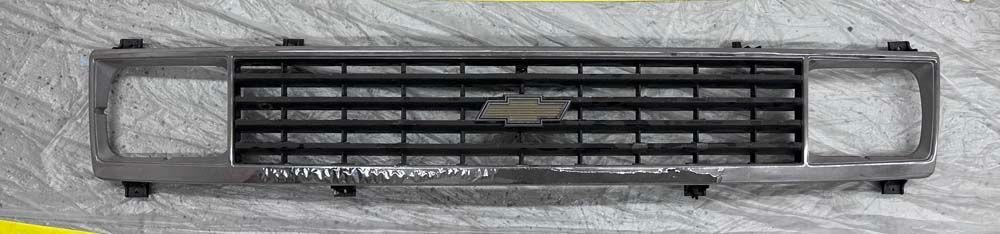 A chevrolet grill is sitting on a white surface.