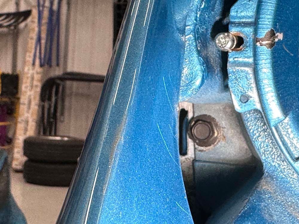 A blue car is parked in a garage next to a stack of tires.