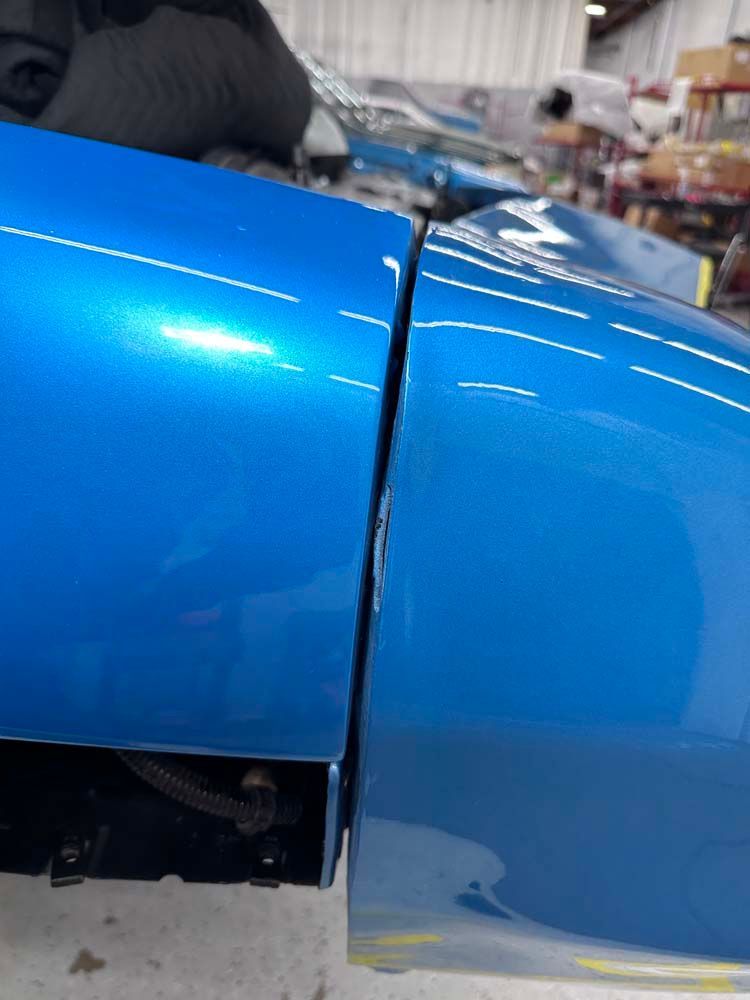 A close up of a blue car 's fender in a garage