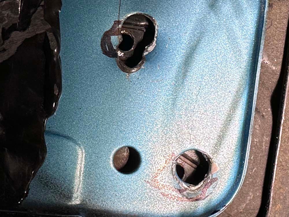 A close up of a blue metal surface with two holes in it.