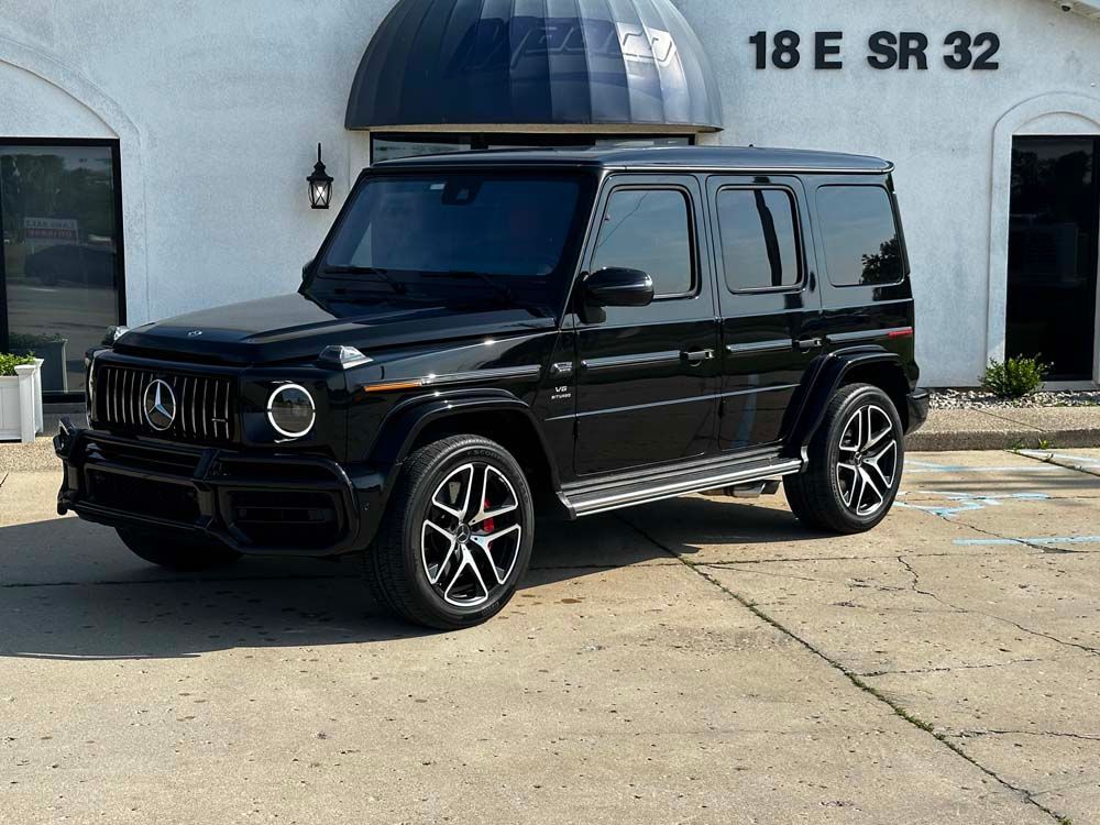 A black mercedes benz g63 amg is parked in front of a building.