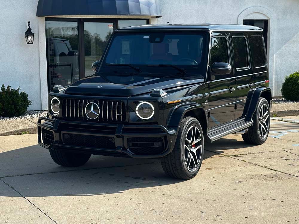 A black mercedes benz g63 amg is parked in front of a building.