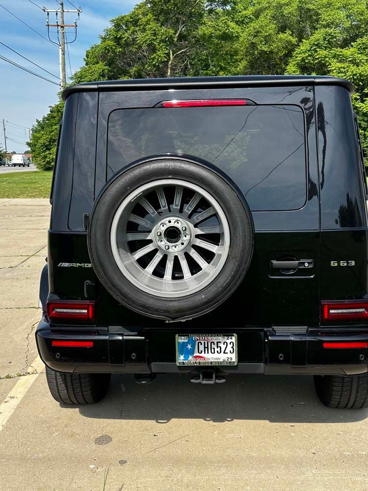 A black jeep with a spare tire is parked in a parking lot.