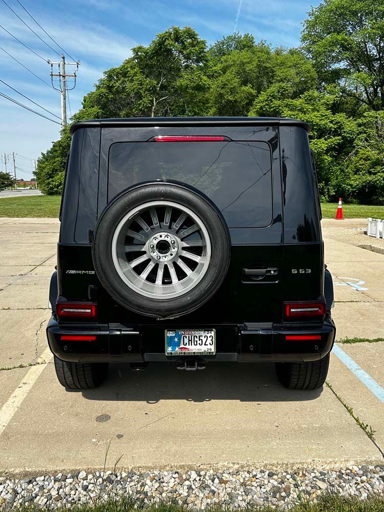 A black mercedes benz g63 is parked in a parking lot.