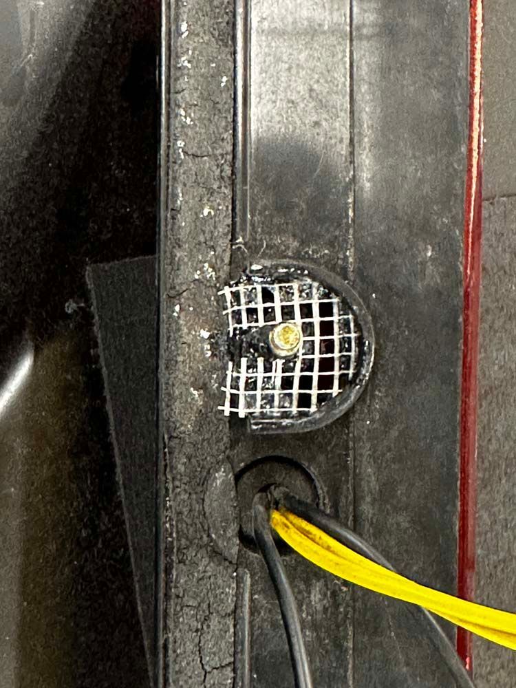 A close up of a car tail light with wires coming out of it.