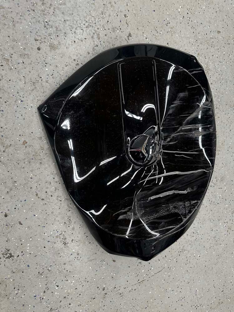 A broken black object is sitting on a gray surface.