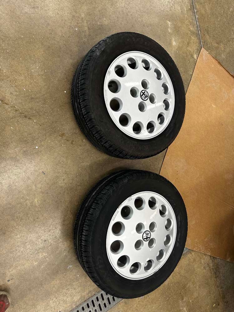 Two wheels and tires are sitting on a concrete floor.