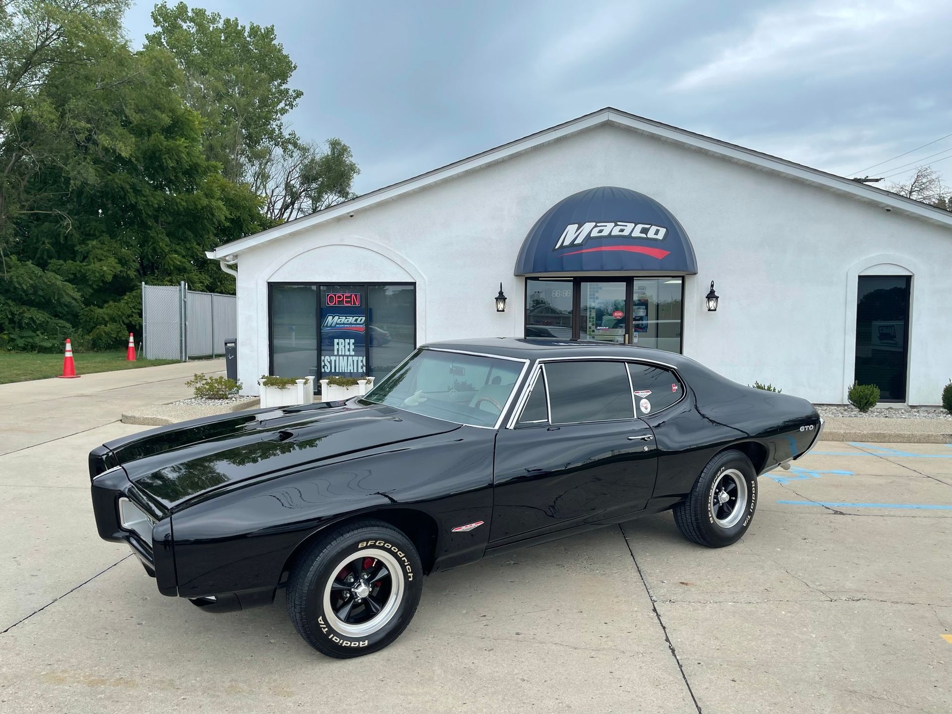 A black car is parked in front of a white building.