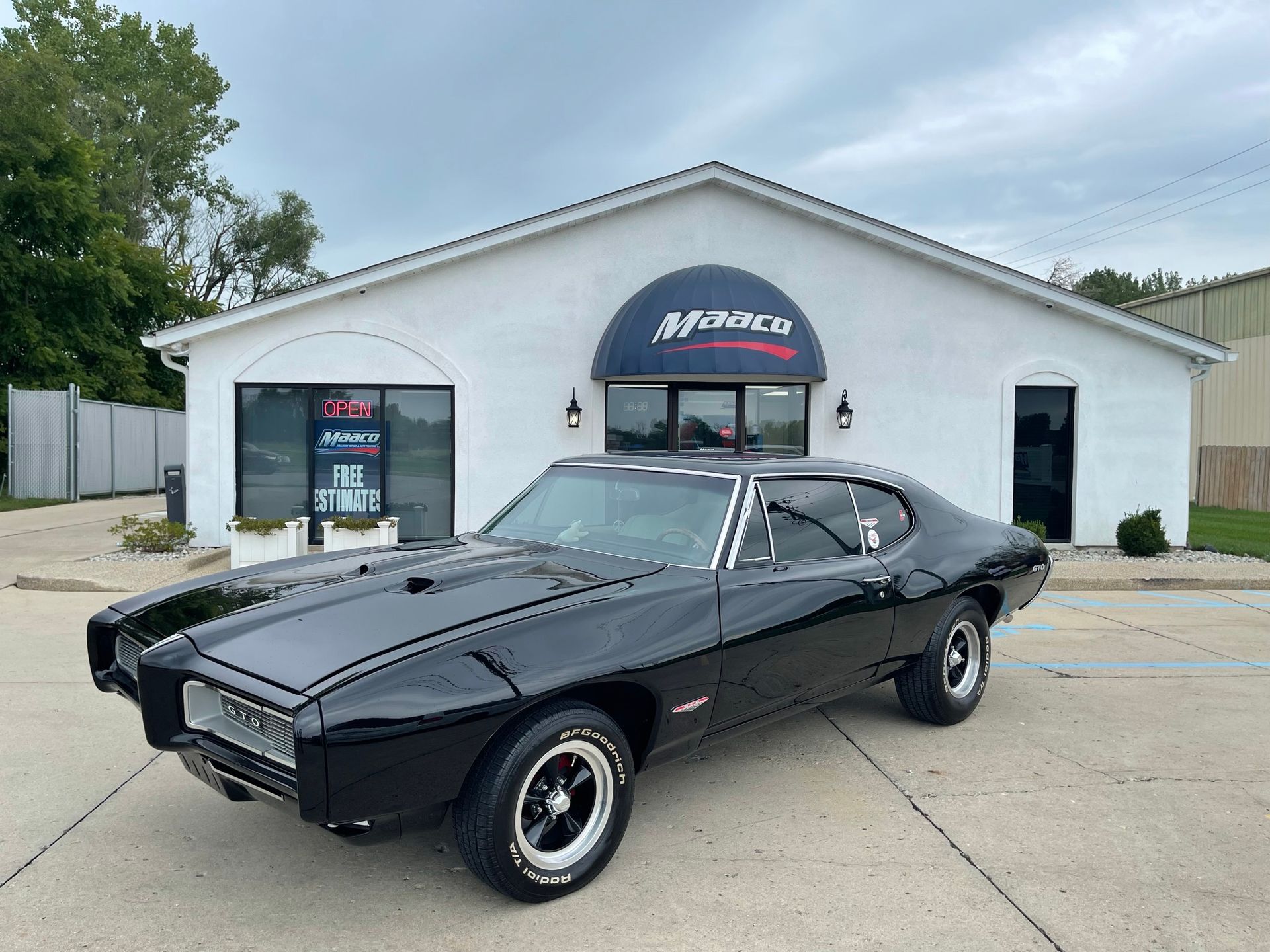 A black car is parked in front of a white building.