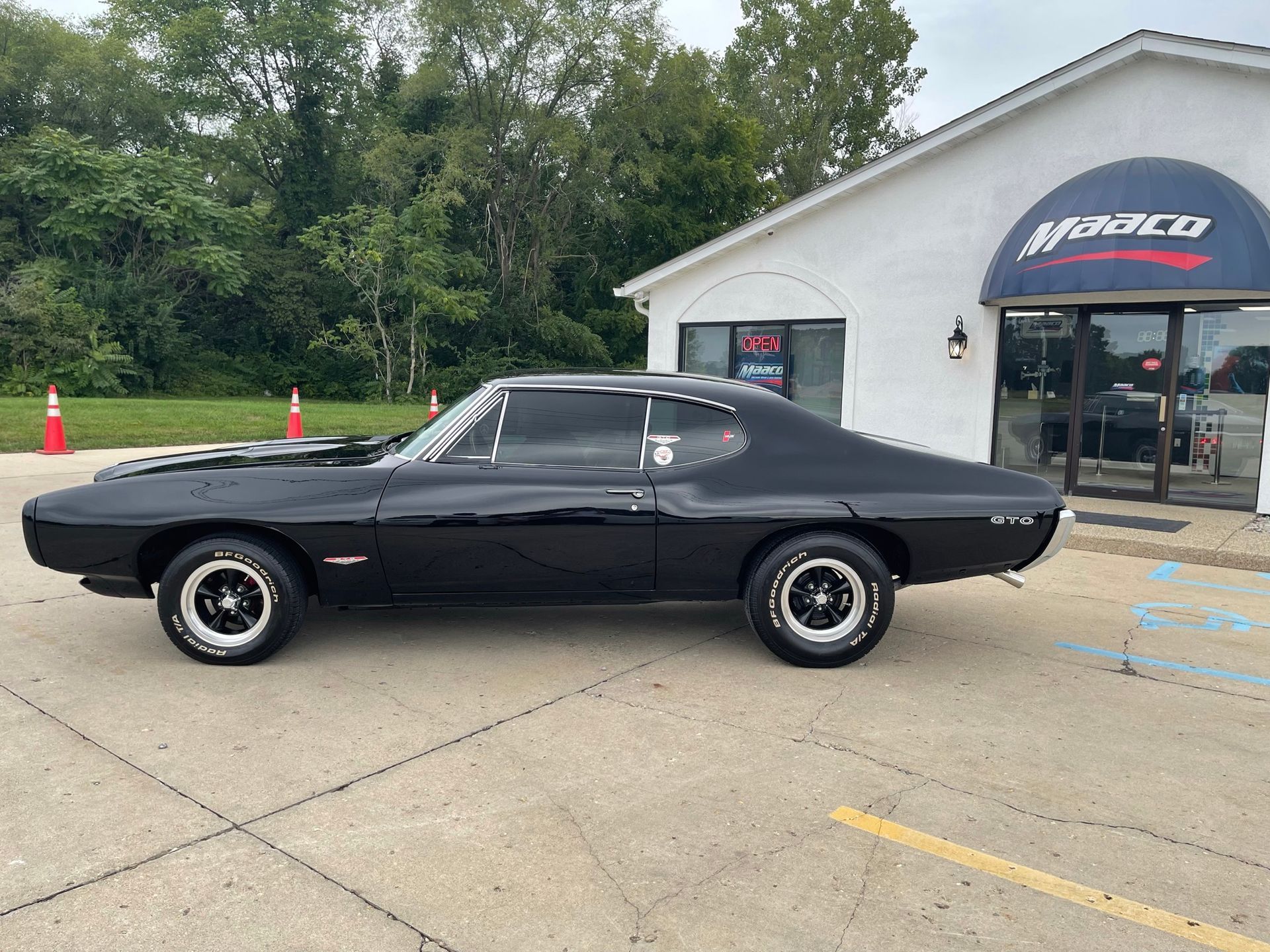 A black car is parked in front of a white building.