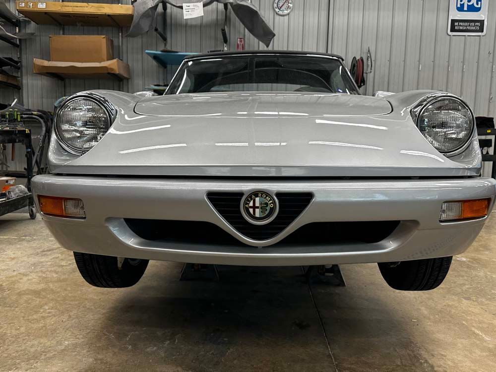 The front of a silver car is parked in a garage.