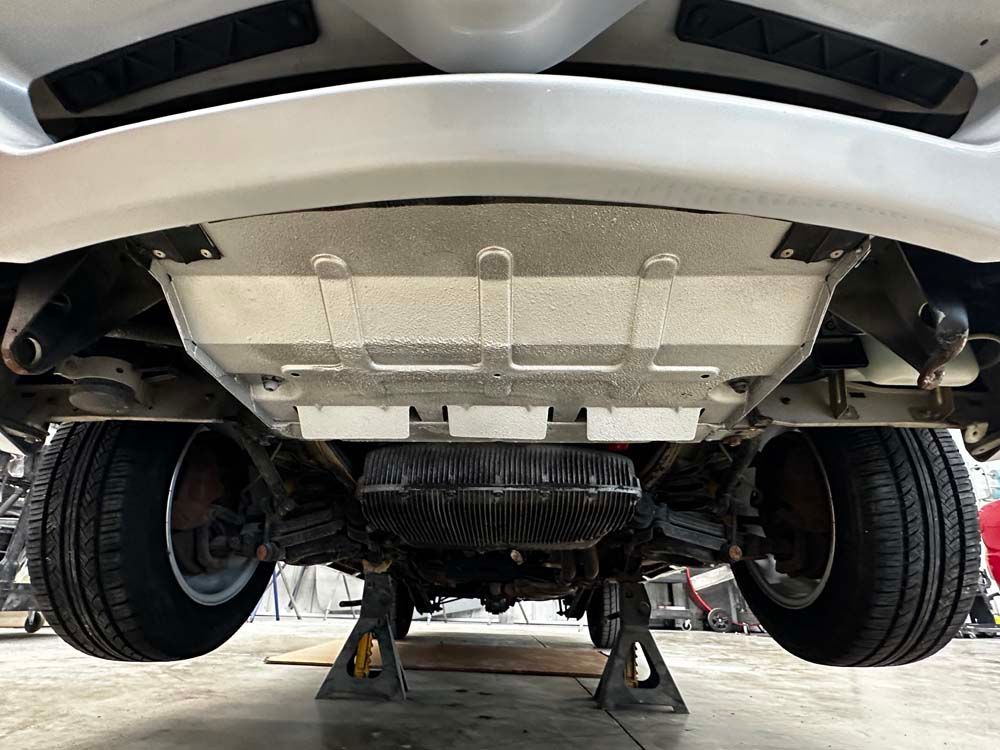 The underside of a car is sitting on a jack.