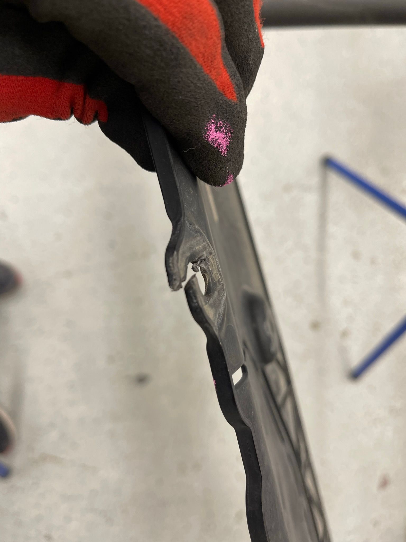 A person wearing red and black gloves is holding a piece of plastic.