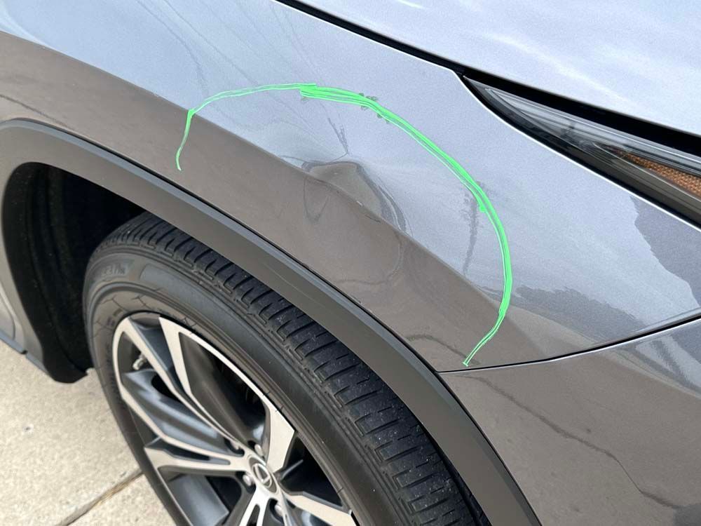 A close up of a car 's fender with a green line drawn on it.
