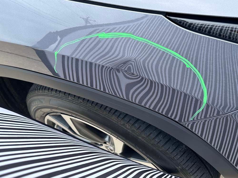 A close up of a car 's fender with a green stripe on it.
