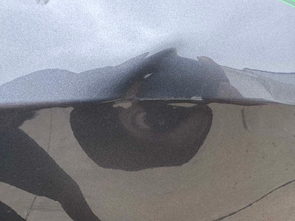 A close up of a car 's bumper with a shadow of a person on it.