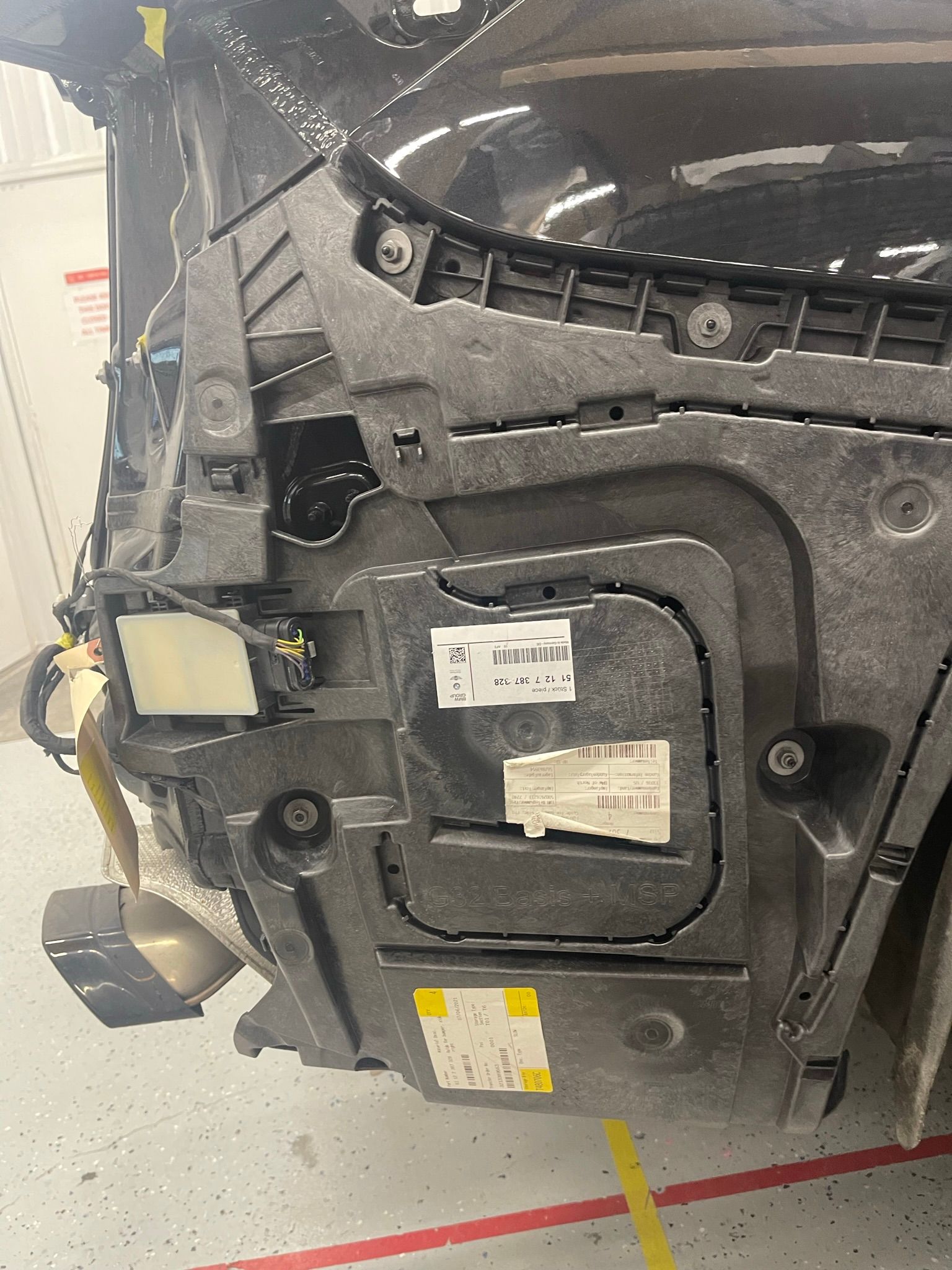 A black car is being dismantled in a garage.