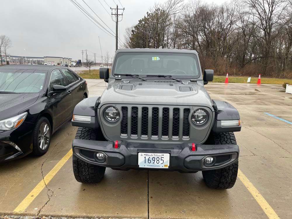 A jeep is parked in a parking lot next to a black car.