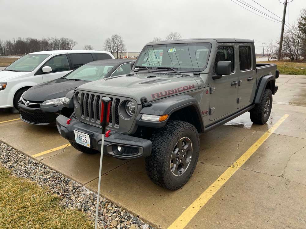 A jeep is parked in a parking lot next to other cars.
