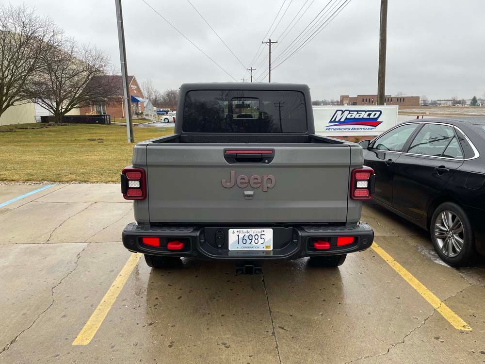 A jeep is parked in a parking lot next to a car.
