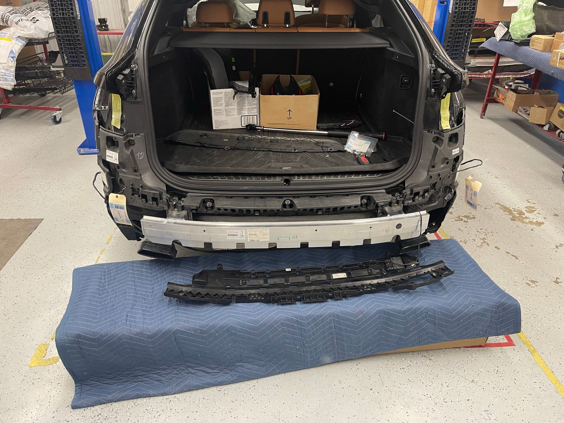 The back end of a car is sitting on a blue mat in a garage.