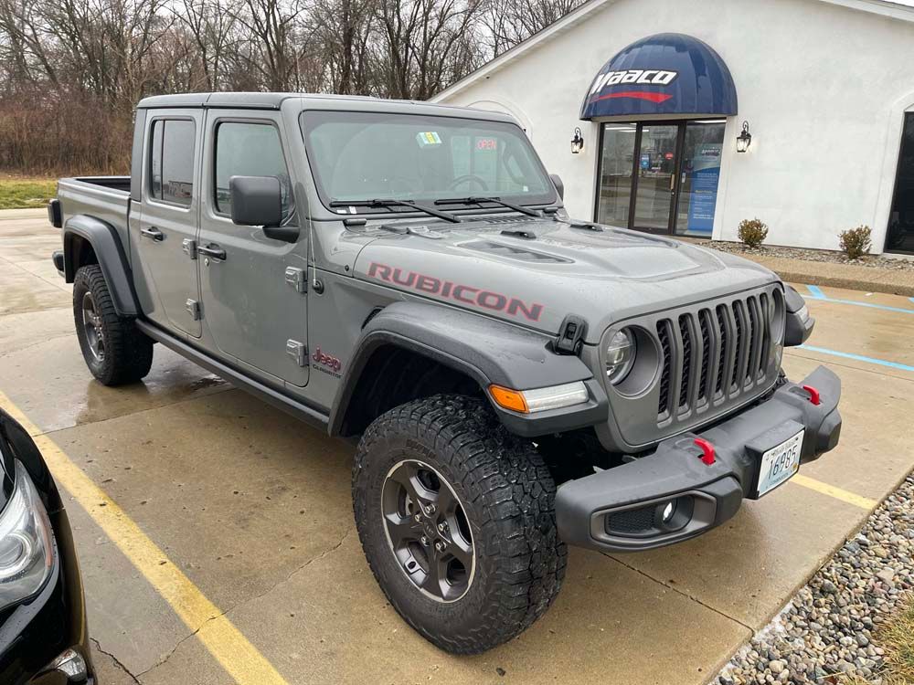 A jeep wrangler rubicon is parked in a parking lot in front of a building.