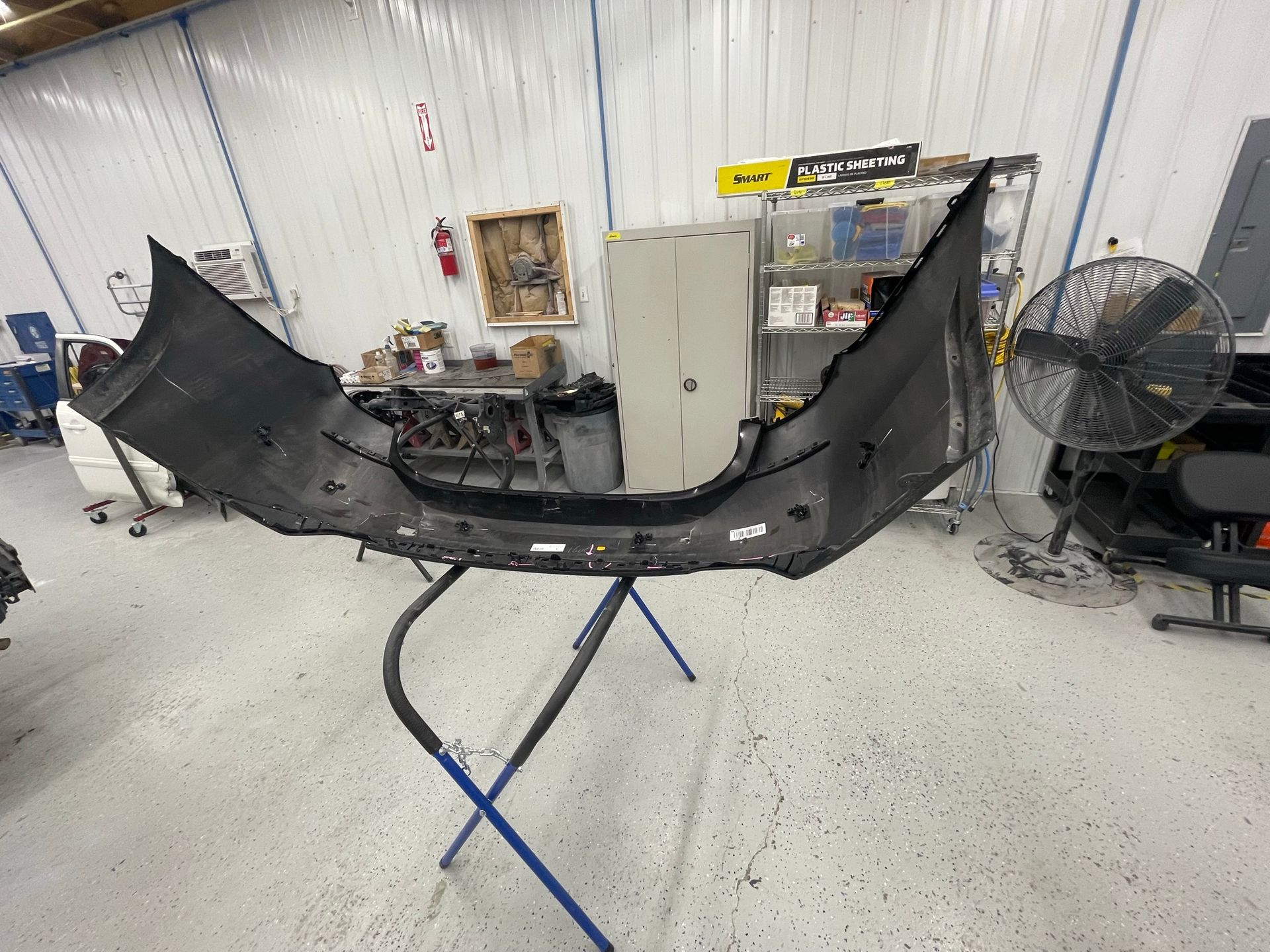 A car bumper is sitting on a stand in a garage.