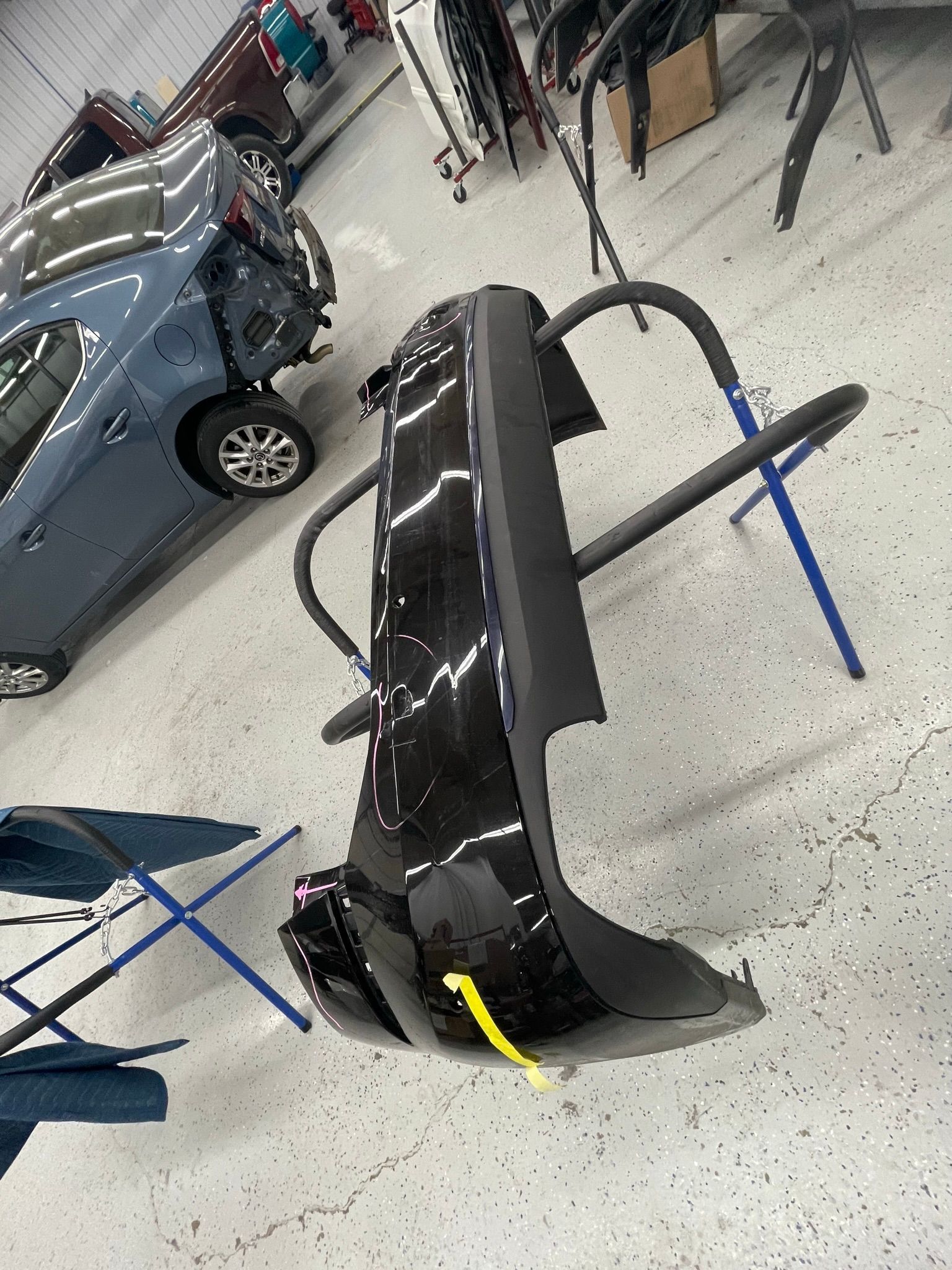 A car with a broken bumper is sitting in a garage.