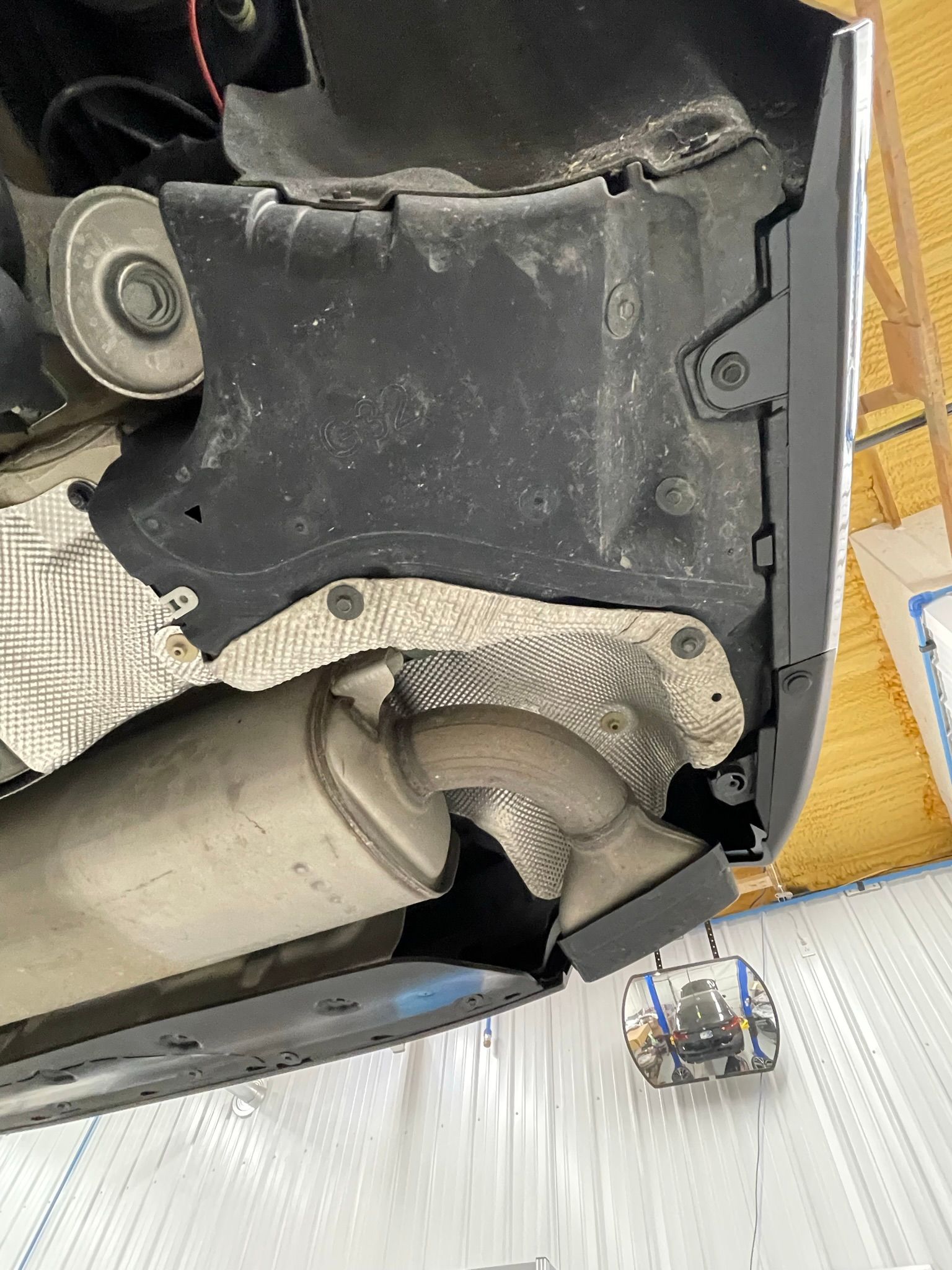 A close up of the underside of a car with a broken exhaust pipe.