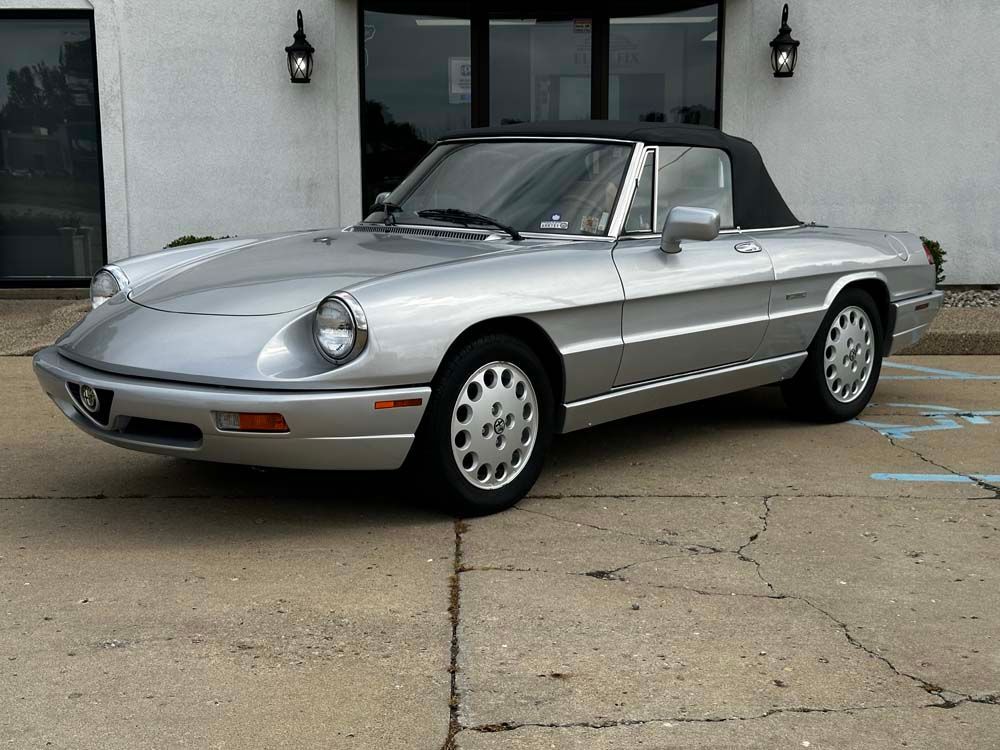 A silver sports car is parked in front of a building.