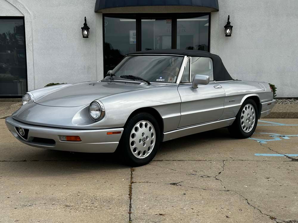 A silver sports car is parked in front of a building.