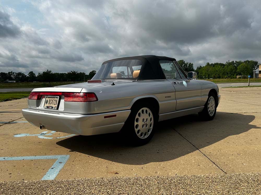 A silver convertible is parked in a parking lot