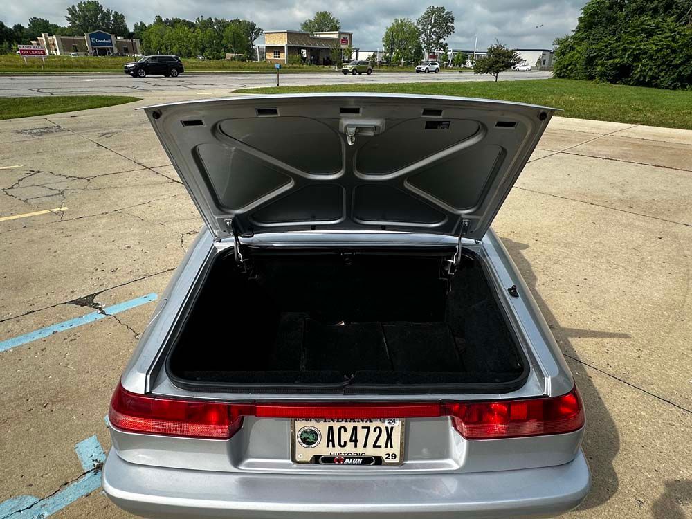 A silver car with the trunk open and a license plate that says ac472x