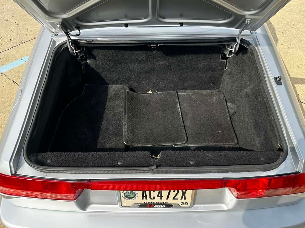 The trunk of a silver car with a license plate that says ac472x