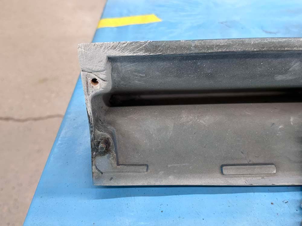 A piece of metal is sitting on top of a blue table.