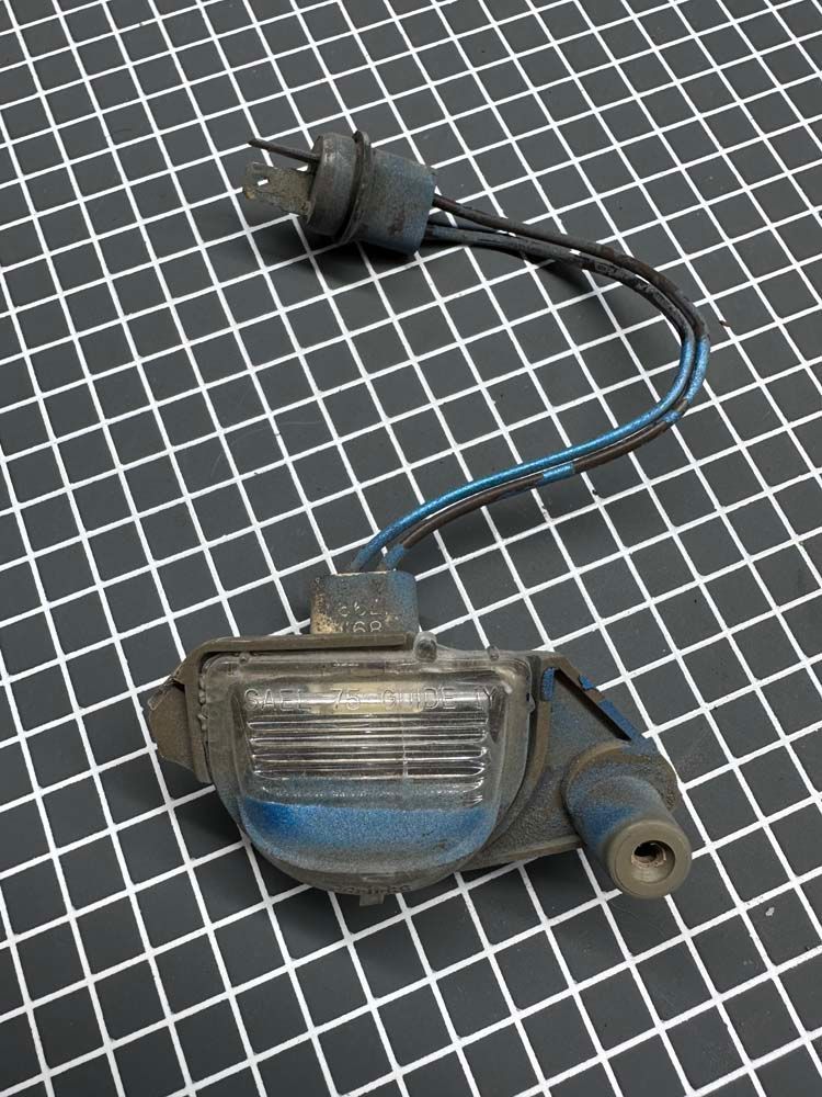 A close up of a license plate light on a checkered surface