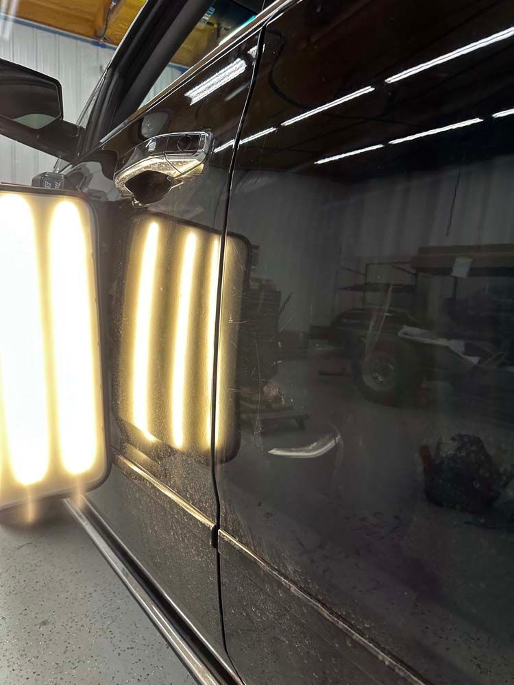 A black car is sitting in a garage with a lot of lights on it.