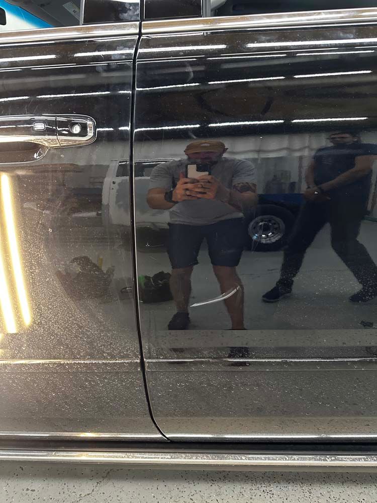 A man is taking a picture of himself in the mirror of a car.