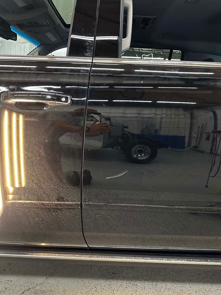 A black car is parked in a garage with the door open.