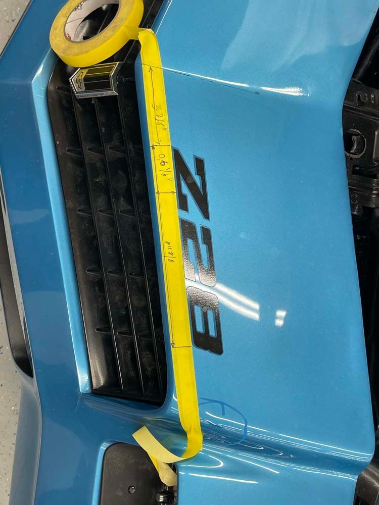 A blue car with a yellow tape measure on it