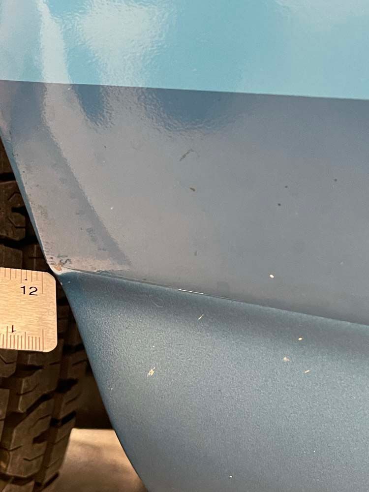 A close up of a blue car with a ruler on it.