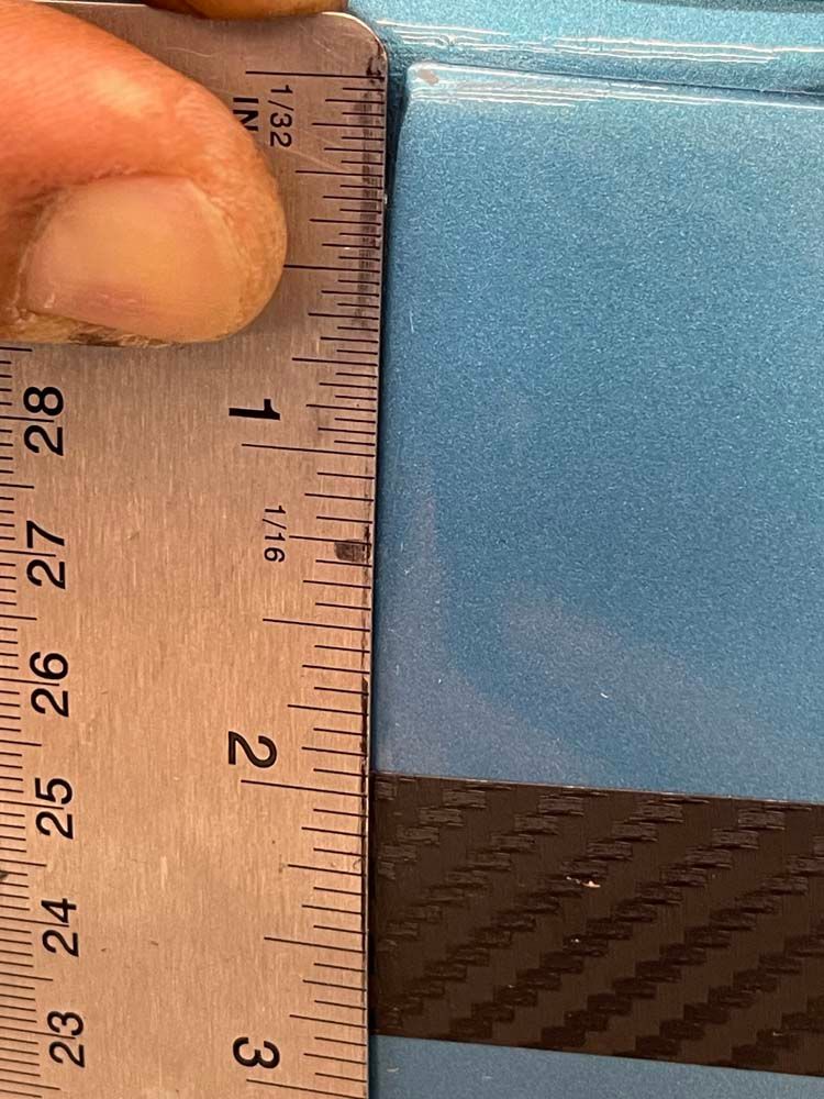 A person is measuring a piece of blue foam with a ruler.