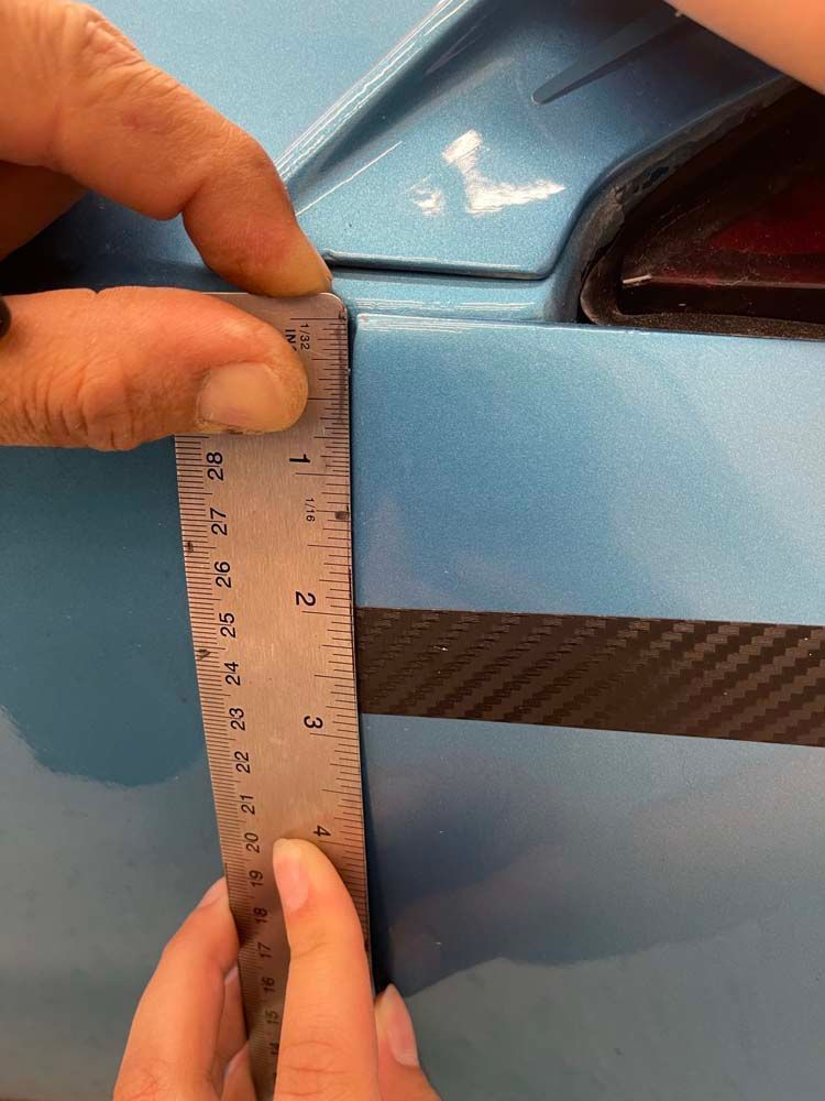 A person is measuring the length of a car with a ruler.