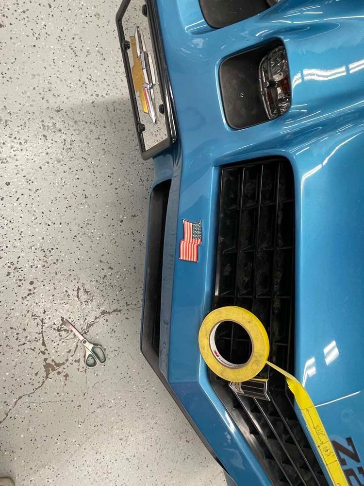A close up of a blue car with a yellow tape on it.