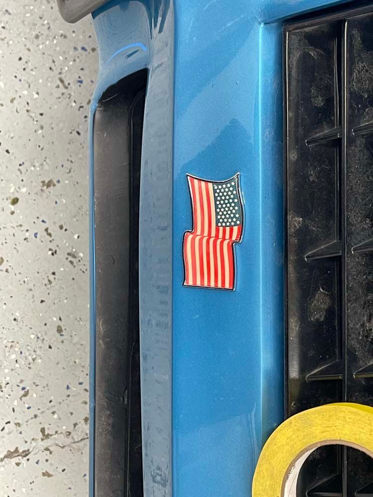 A blue car with a sticker of an american flag on it.