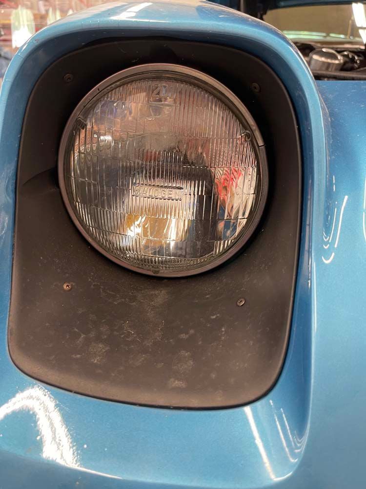 A close up of a headlight on a blue car
