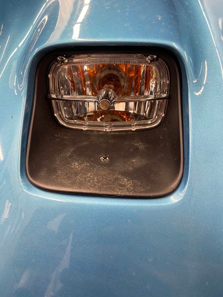 A close up of a headlight on a blue car.
